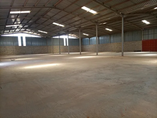 Kampala warehouse interior with clear-span storage space ready for short-term tenant occupation, showing roller shutter doors and concrete floor.