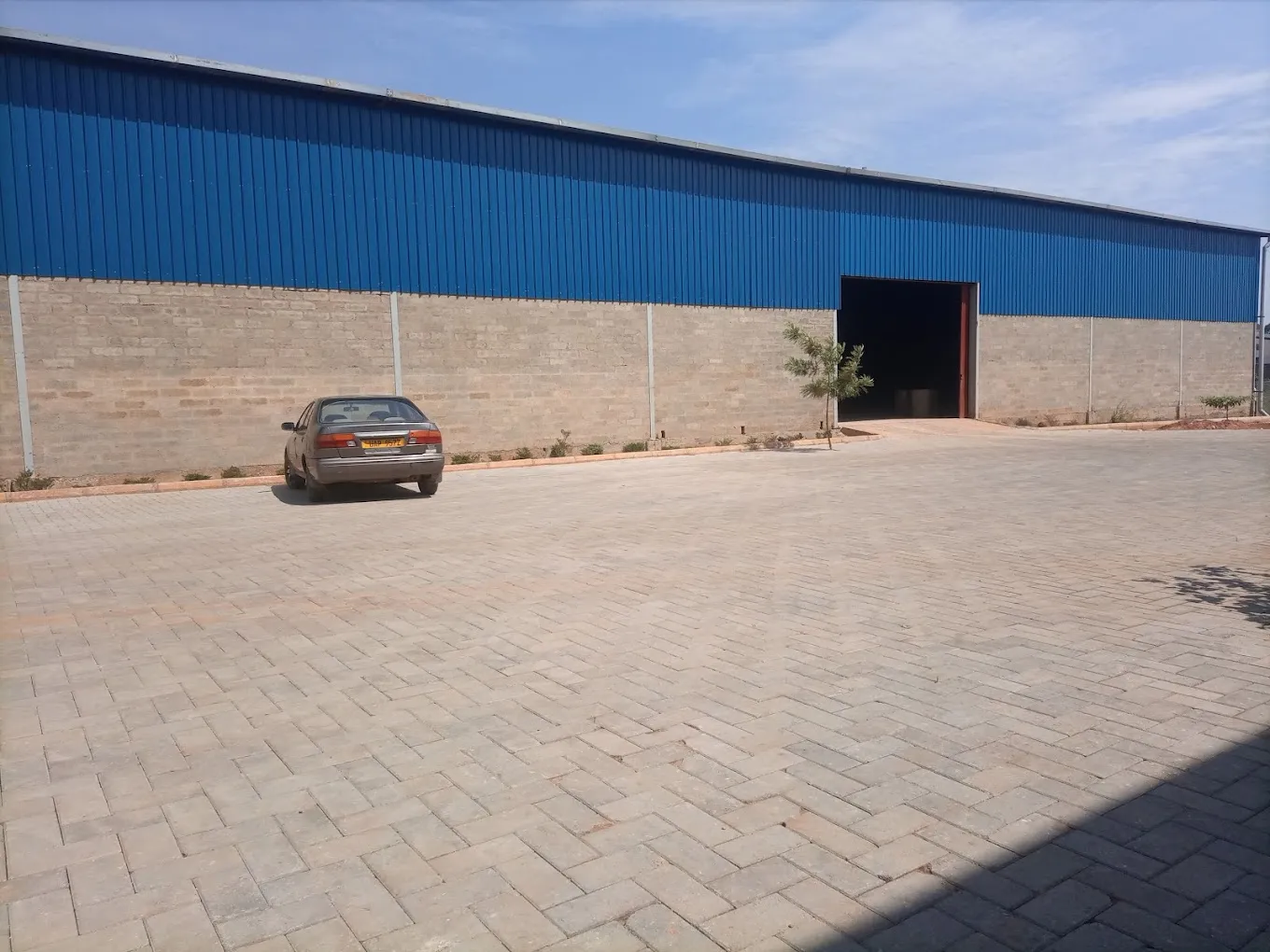 Wide interior view of a clean Kampala warehouse with high ceilings, concrete floors, and loading dock doors.